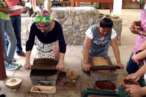 Two women grinding cacao on a metate. 