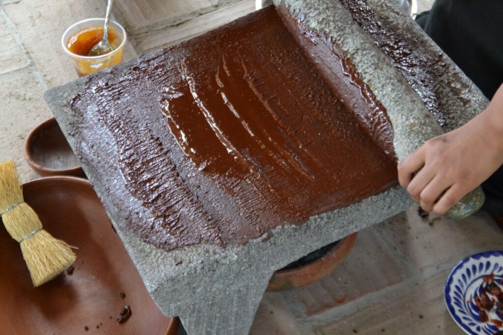 woman grinding cacao on a metate into a liquid paste