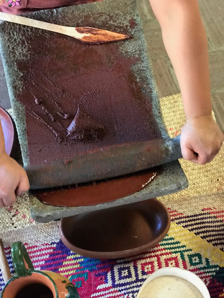 woman grinding cacao on a metate. cacao is liquid. 