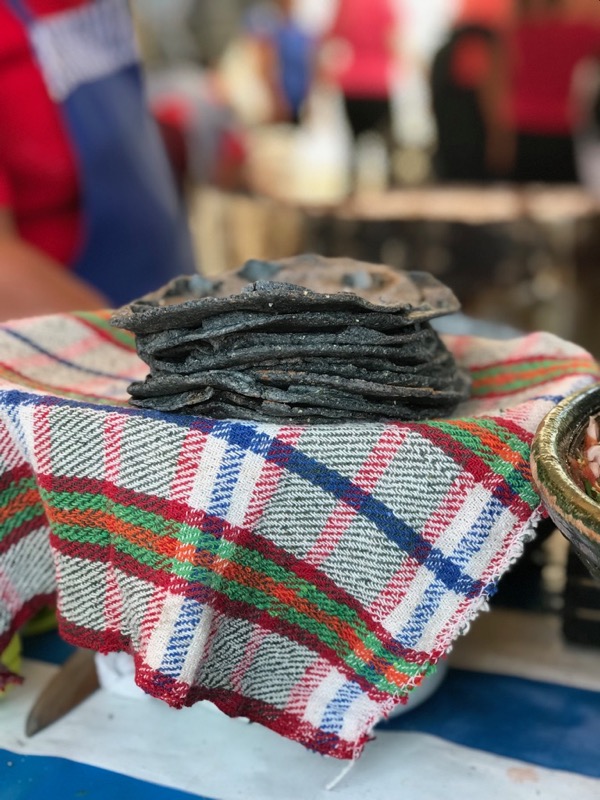Blue corn tortillas in a stack at a market wrapped in a cotton towel